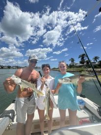Three anglers proudly displaying their catch of Snook while enjoying a sunny day on the water.