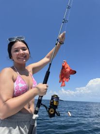 A young angler proudly displaying a vibrant Red Snapper while fishing offshore, showcasing a sunny day on the water.