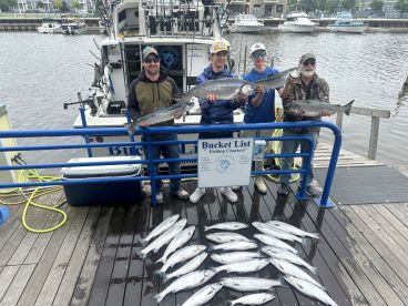 A group of anglers proudly displaying their catch of salmon at the dock after a successful fishing trip with Bucket List Fishing Charters.