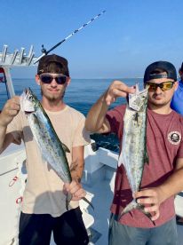 Two anglers proudly displaying their catches of Spanish Mackerel while fishing on a sunny day.
