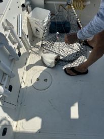 A fisherman is actively reeling in a flatfish on a boat, showcasing the excitement of the catch during a fishing trip.