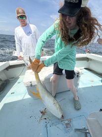 A young angler reeling in a large fish on a boat, showcasing the excitement of fishing in open waters.