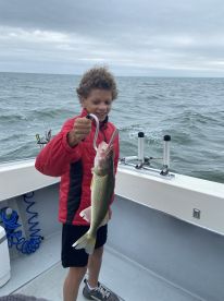 A young angler proudly displaying a Walleye while fishing on a boat, showcasing the excitement of a successful catch.