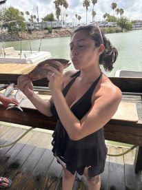 An angler joyfully posing with a Spotted Sea Trout at a dock, showcasing a memorable catch after a fishing trip.