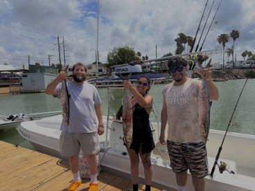 Three anglers proudly displaying their catch of Spanish Mackerel at the dock after a successful fishing trip.