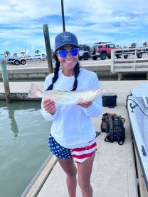 An angler proudly displaying a Speckled Trout at the dock, showcasing a vibrant fishing environment.