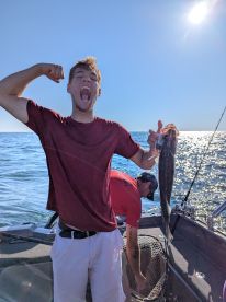 Excited angler celebrating with a freshly caught fish aboard a fishing boat, showcasing a vibrant ocean backdrop.