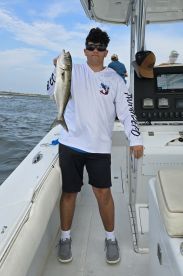 A young angler proudly displaying a caught fish while aboard a fishing boat, showcasing a successful day on the water.