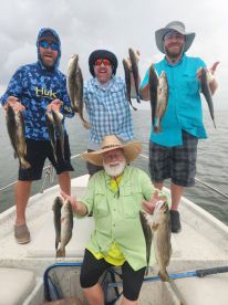 Group of anglers proudly displaying their catch of Speckled Trout aboard a fishing boat, showcasing a successful day on the water.