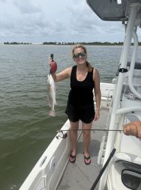 An angler proudly displaying a freshly caught Redfish while standing on a boat, showcasing a successful day of fishing in coastal waters.