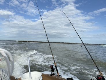 A fishing boat navigating through the water with fishing rods ready for action, showcasing a dynamic fishing environment.