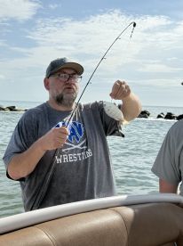 An angler proudly displaying a freshly caught fish while fishing from a boat in a coastal environment.