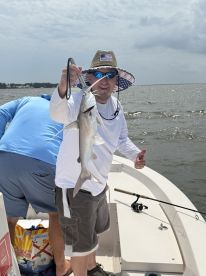 An angler proudly displaying a freshly caught fish while fishing on a boat, showcasing a sunny day on the water.