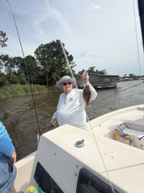 An angler proudly displaying a Flounder while fishing from a boat in a calm waterway, showcasing a successful catch during a relaxing day on the water.