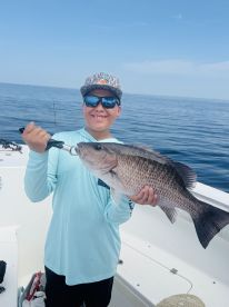 A young angler proudly displaying a large Snapper while fishing on a boat in open waters.