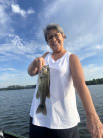 An angler proudly displaying a large Largemouth Bass while fishing on a serene lake, showcasing a beautiful day outdoors.