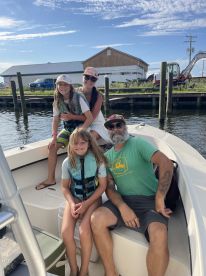A family enjoying a day on a boat, with two children and an adult seated comfortably, showcasing a fun and relaxed fishing environment.