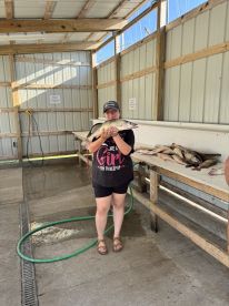 A young angler proudly displaying a large catfish at a cleaning station, showcasing a successful fishing trip.