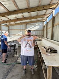 Angler proudly displaying a catch of fish at a cleaning station, showcasing a successful day of fishing.