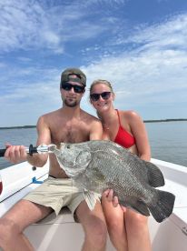 A couple proudly displaying a large Black Drum while enjoying a day on the water.