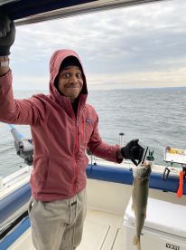 A young angler proudly displaying a caught fish while fishing on a boat, showcasing a fun day on the water.