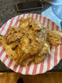 A plate of freshly cooked fish fillets, likely from a recent fishing trip, showcasing a delicious meal prepared at home.