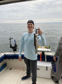 Young angler proudly displaying a caught fish aboard a fishing boat, showcasing a successful day on the water.