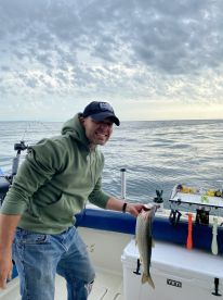 An angler proudly displaying a freshly caught fish while aboard a fishing boat, with a serene ocean backdrop.