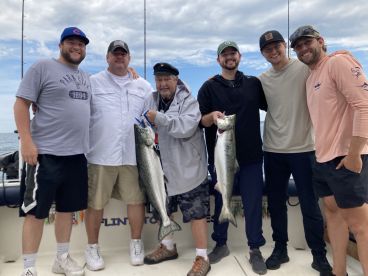 Group of anglers proudly displaying their catch of Salmon aboard a fishing charter, showcasing a successful day on the water.