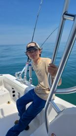 A young angler relaxing on the boat's interior, ready for a fishing adventure on calm waters.