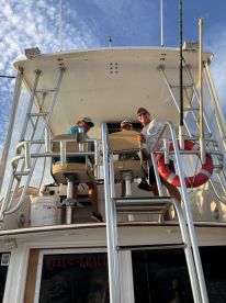 Three individuals enjoying the view from the helm of the 'Reel Grace' fishing boat, showcasing its spacious design and inviting atmosphere.