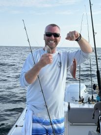 An enthusiastic angler proudly displaying his catch of a Snapper and a small fish while fishing offshore.