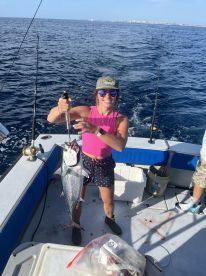 Angler proudly displaying a large fish on a boat during a deep-sea fishing trip.
