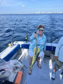 A smiling angler holding a vibrant Mahi Mahi while fishing offshore, showcasing a successful catch on a sunny day.