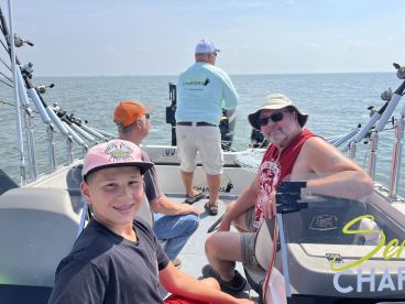 A young angler with braces enjoys a day on the boat with family, showcasing a relaxed fishing atmosphere.