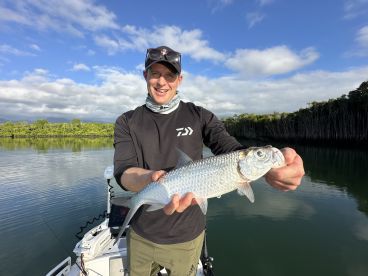 Angler proudly displaying a Silver Bream while fishing in a serene river environment.