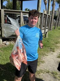 A young angler proudly displaying a bag of freshly caught Red Snapper after a successful fishing trip.
