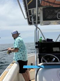 An angler actively fishing from a center console boat in open water, showcasing a vibrant fishing environment.