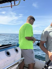 Two young anglers actively fishing on a boat, with one wearing a bright yellow shirt, enjoying a day on the water.