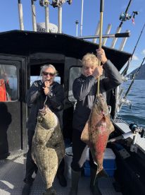 Two anglers proudly displaying their catch of large Halibut aboard a fishing charter, showcasing a successful day on the water.