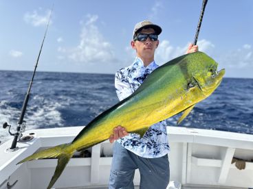 A young angler proudly displaying a vibrant Mahi Mahi while fishing offshore, showcasing the excitement of a successful catch.
