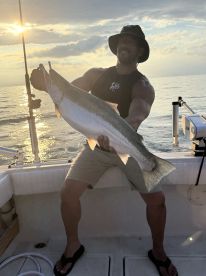 Angler proudly displaying a large fish during a sunset fishing trip on a boat.