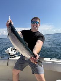 A young angler proudly displaying a large Salmon while fishing on a sunny day.