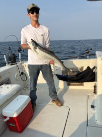 A young angler proudly displaying a large fish on a fishing boat, enjoying a day on the water.