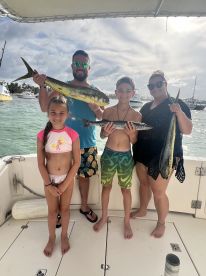 A family proudly displaying their catch of Mahi Mahi while enjoying a day on the water, showcasing a fun fishing experience.