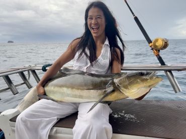 An excited angler proudly displays a large fish while seated on a boat, showcasing a successful fishing trip in open waters.