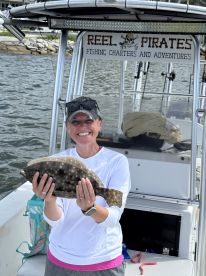 A smiling angler proudly displaying a Flounder on a fishing charter boat, showcasing a successful day on the water.