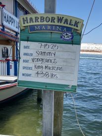 Signboard at HarborWalk Marina displaying details of a King Mackerel catch, including the angler's name and weight.