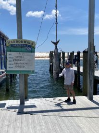 Young angler proudly displaying a large King Mackerel at HarborWalk Marina, showcasing a successful fishing trip.