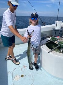 A young angler proudly displaying a large fish while fishing on a boat, showcasing a fun day out on the water.